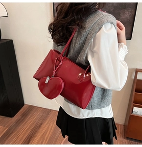 Glossy red Boston bag with heart-shaped pendant shown on a model for daily styling