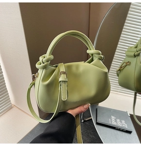 Detail of pistachio green bucket bag featuring knotted handle and gold metal hardware