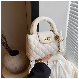 Detail of white quilted crossbody bag with gold hardware and elegant chain strap