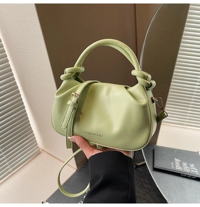 Close-up of light green pleated leather bag with knotted handle and fashion lettering