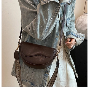 Detail of dark brown saddle bag with vintage woven wide strap and smooth PU leather