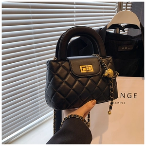 Detail of black quilted chain bag with gold metal ball adjuster and leather strap