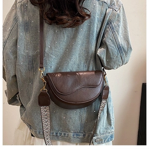 Detail of vintage dark brown saddle bag featuring ethnic wave pattern woven strap