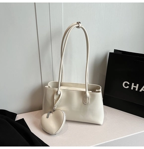 Close-up of cream leather tote bag featuring a detachable heart-shaped coin purse accessory