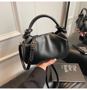 Detail of black pleated bucket bag with braided handle and gold-tone hardware accents
