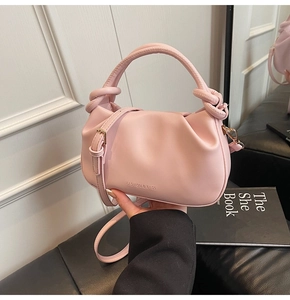 Detail showing pink pleated bucket bag with knotted handle and fashion branding