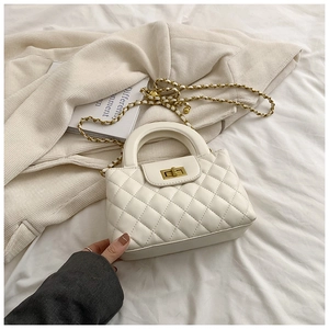 Detail showing the white quilted pattern and gold twist lock closure of the handbag