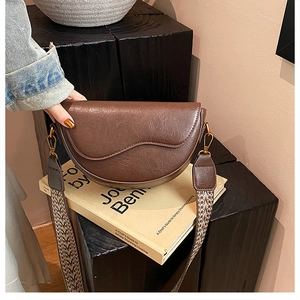 Detail of vintage dark brown saddle bag with textured leather and woven ethnic strap