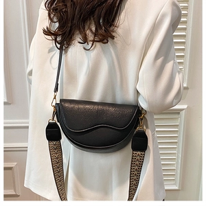 Detail of black saddle bag with lychee texture and wide bohemian jacquard strap