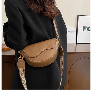 Detail of a brown saddle bag featuring vintage wrinkled texture and ethnic woven strap