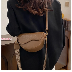 Brown saddle bag shown with two interchangeable leather and woven shoulder straps