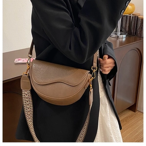 Detail of dark brown saddle bag with textured leather and woven pattern strap