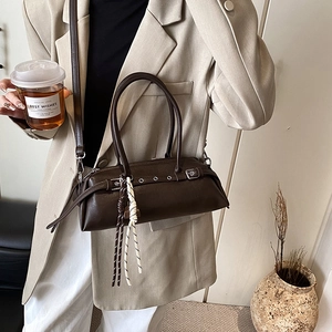 Minimalist dark brown leather baguette shoulder bag with stylish grommet strap and charms