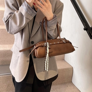 Retro brown leather baguette bag with belt buckle details and woven pendant on model