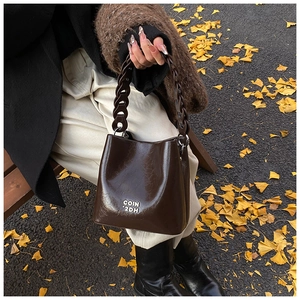 Détail d'un sac seau vintage en cuir marron foncé avec lettrage argenté sur le devant