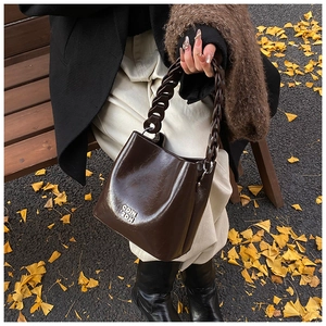 Détail d'un sac seau vintage en cuir ciré marron foncé avec logo argenté COIN 2DH