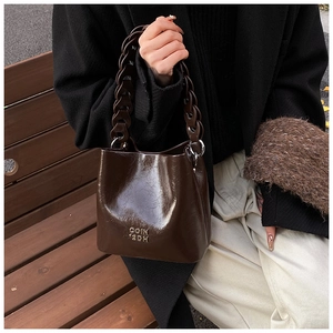 Détail du sac seau vintage en cuir ciré avec poignée chaîne épaisse et logo en métal