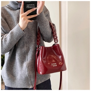 Détail du sac seau bordeaux avec texture en cuir vintage et double bandoulière