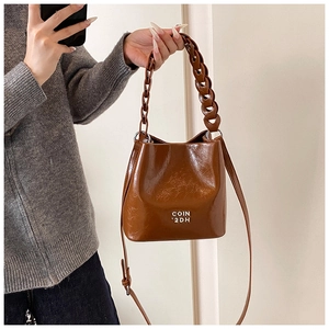Détail du sac seau vintage en cuir huilé avec logo COIN 2DH argenté et poignée chaîne