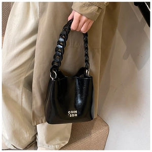 Détail du sac seau noir en cuir ciré avec lettrage doré et bandoulière chaîne épaisse