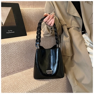 Détail du sac seau en cuir ciré noir avec logo doré et poignée en chaîne épaisse