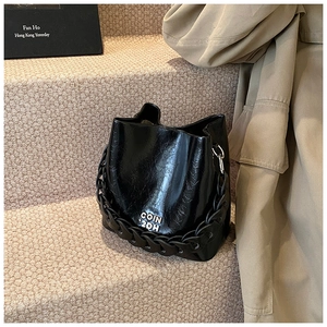 Détail du sac seau noir brillant en cuir ciré avec logo métallique COIN 2DH élégant