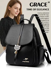 Detail of black pebbled leather backpack with gold logo and cute cat charm pendant