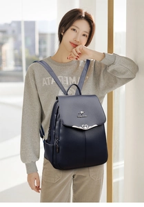 Detail of navy blue leather backpack featuring a silver kangaroo logo and heart buckle