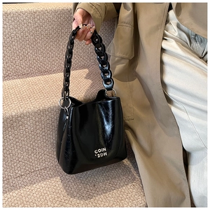 Détail d'un sac seau en cuir ciré vintage avec une grosse chaîne et un lettrage COIN