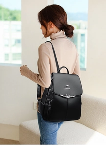 Detail of black faux leather backpack with silver kangaroo logo on textured material