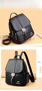 Macro view of black litchi leather backpack with golden kangaroo logo and cat charm