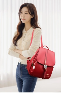 Close-up of red lychee texture leather backpack with cat pendant and metal accents