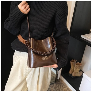 Détail du sac seau marron café avec poignée tressée et bandoulière sur mannequin