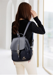 Detail of navy blue pebble leather backpack with gold kangaroo logo and cat charm