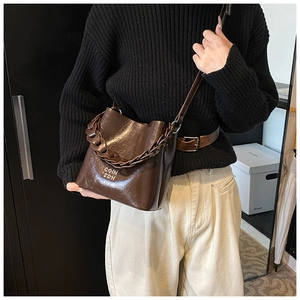 Détail du sac seau en cuir ciré marron avec chaîne décorative et logo COIN ZDH