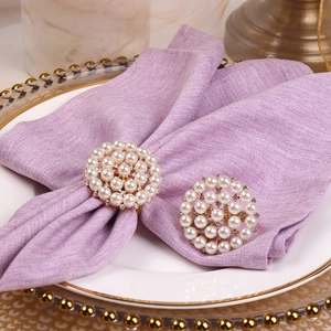 Set of gold napkin rings with pearls and rhinestones on lavender napkin for wedding