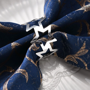 Silver hollow star napkin ring with metallic finish on dark blue fabric setting