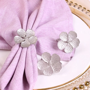 Matte silver plum blossom napkin ring with 3D petals on a lilac fabric napkin