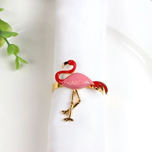 Elegant gold flamingo napkin ring with pink enamel detail on a white linen napkin