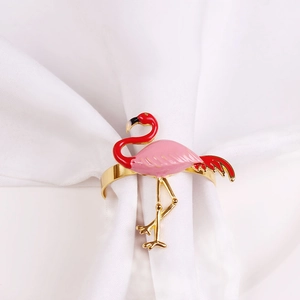 Golden flamingo napkin ring with pink enamel detail on elegant white dining cloth