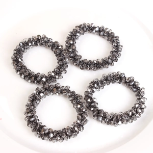 Close-up of four dark grey faceted crystal bead napkin rings on a white ceramic plate