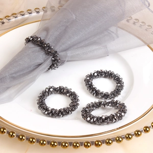Set of 4 smokey grey crystal beaded napkin rings on an elegant white ceramic dinner plate