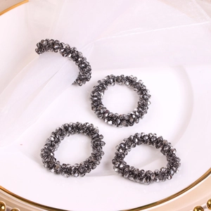 Detail of charcoal grey crystal beaded napkin rings set on elegant white ceramic plate