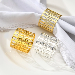 Elegant gold and silver hollow geometric metal napkin rings set on a white dinner plate