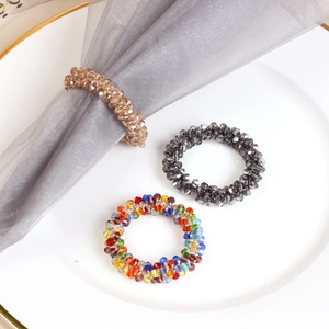 Three-color crystal beaded napkin rings in champagne gold and grey on a white ceramic plate