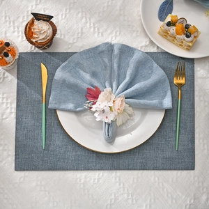 Detail view of white rose napkin ring on a light blue napkin with golden rimmed porcelain