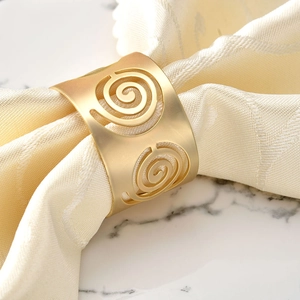 Vue détaillée d'un rond de serviette doré avec motif spirale sur tissu beige texturé