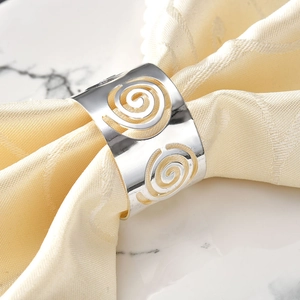 Rond de serviette argenté à motif spirale ajouré sur serviette beige et marbre