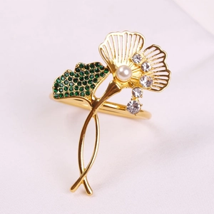 Detailed close-up of a golden ginkgo leaf napkin ring with green crystals and a pearl