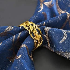 Macro view of gold braided metal napkin ring on blue jacquard fabric for table decor